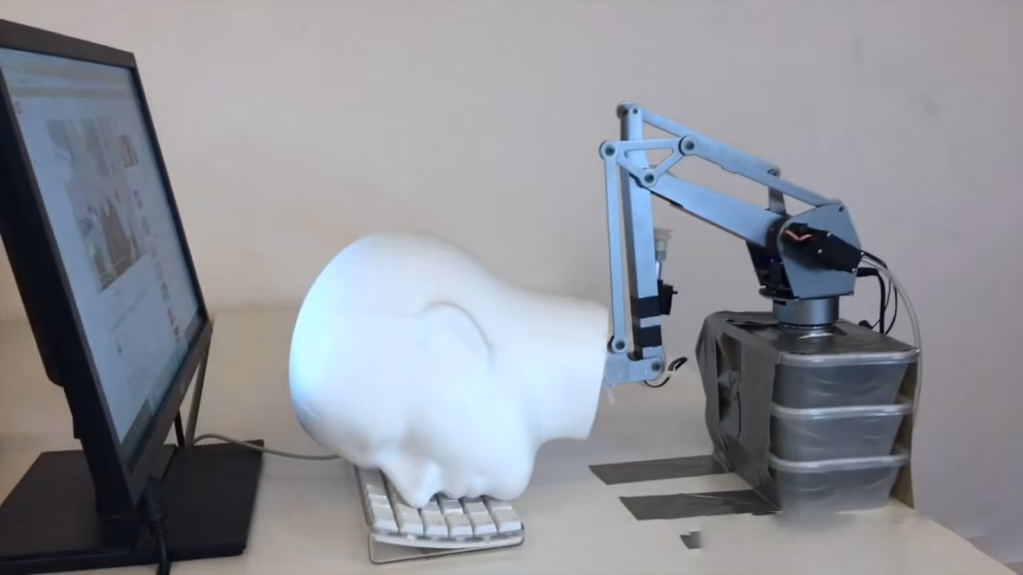 Cabeça robótica, toda branca, sobre um teclado de computador.